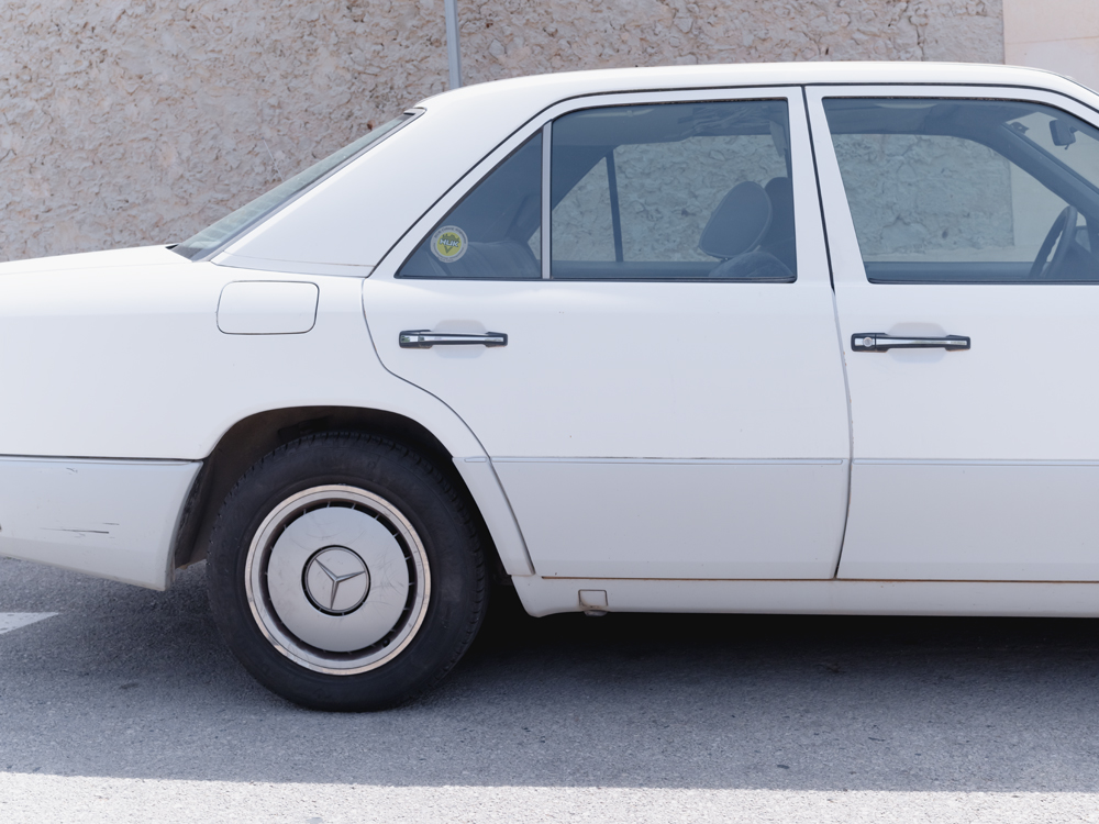 parked white mercedes car on the street in mallorca, photo by jeroen van de gruiter, 2024